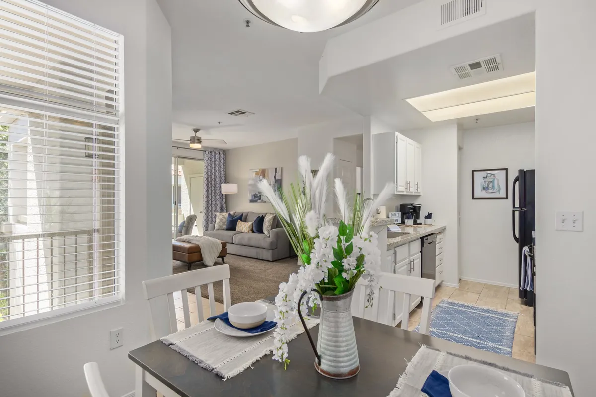 This image features a welcoming open-concept area that seamlessly blends the living room with the dining and kitchen spaces. The plush sofa is positioned for relaxation, and the living area is accented with a smart TV and modern décor elements. Natural light pours in, highlighting the inviting and contemporary atmosphere.