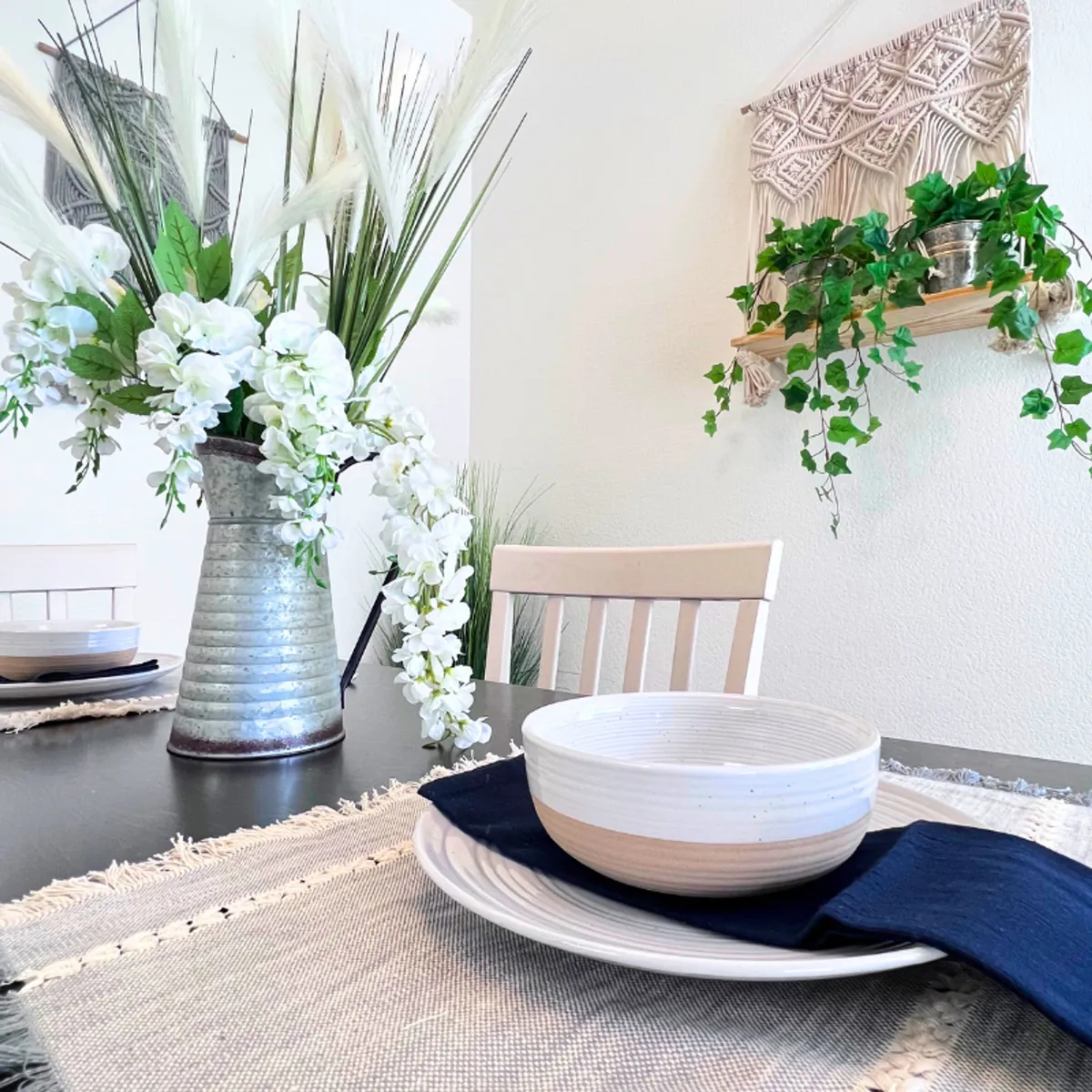A warmly decorated dining area featuring a floral centerpiece, set dinnerware, and a cozy atmosphere. The table is arranged for a meal or gathering, suggesting a welcoming space for guests to connect and enjoy home-cooked meals.