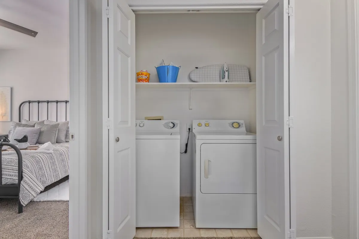 A dedicated laundry area with a washing machine and dryer beneath a tidy shelf holding laundry essentials. The space is organized and functional, offering practical convenience for longer stays.